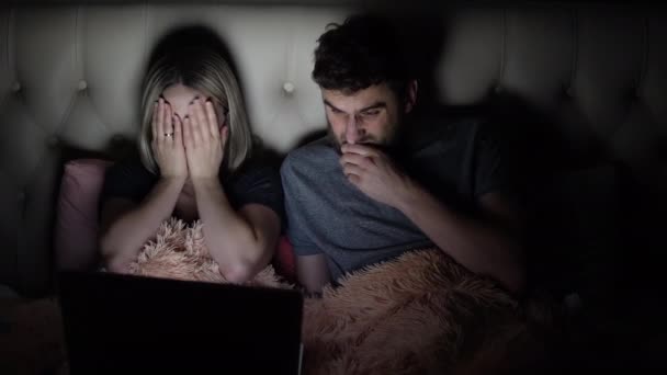 Man och kvinna, unga par tittar skrämmande film på laptop i sängen innan läggdags — Stockvideo