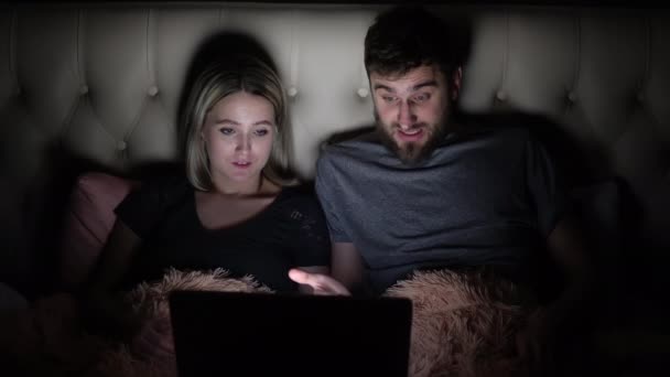 एक आदमी और एक महिला, एक युवा जोड़ा बिस्तर पर बिस्तर पर जाने से पहले एक फिल्म देख रहा है और भावनात्मक रूप से योजना पर चर्चा कर रहा है — स्टॉक वीडियो