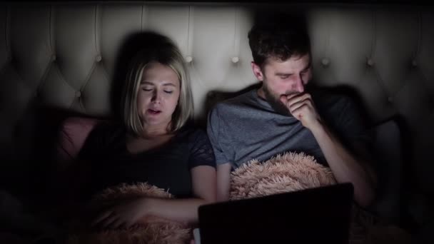Мужчина и женщина, молодая пара, смотрящая скучный фильм на ноутбуке перед сном — стоковое видео