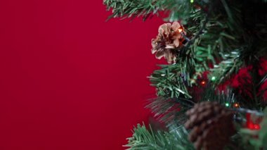 Noel oyuncağının kalbi kırmızı arka planda bir Noel ağacında asılı.