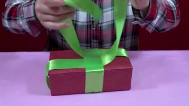 Kadın Noel 'i paketliyor, yeni yıl hediyesini kırmızı ambalaj kağıdına sarıp yeşil kurdeleyi sıkılaştırıyor.