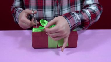 Kadın Noel 'i paketliyor, yeni yıl hediyesini kırmızı ambalaj kağıdına sarıp yeşil kurdeleyi sıkılaştırıyor.
