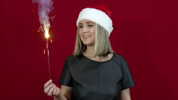 Kırmızı Arka Planda Noel Şapkalı Kadın Elinde Bingala Ateşi Tutuyor — Stok fotoğraf