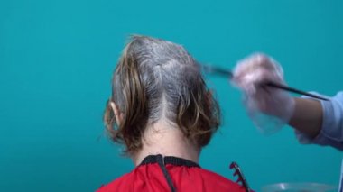 Kuaför, kadının saçını özel bir fırçayla boyuyor. Evde saç boyama