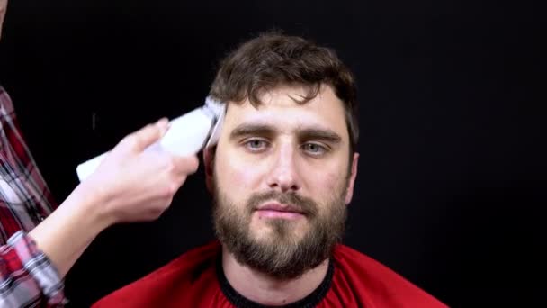 Ein Mann in einem Friseursalon, eine Meisterin schneidet ihr Haar auf schwarzem Hintergrund — Stockvideo