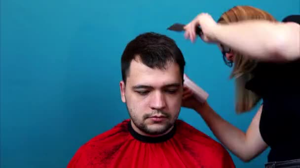 Fusillade temporelle. Une femme coupe un homme cheveux à la maison, dans un salon, en mouvement rapide — Video