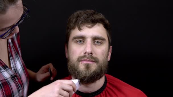 Friseurmädchen schneidet Mann-Bart auf schwarzem Hintergrund — Stockvideo