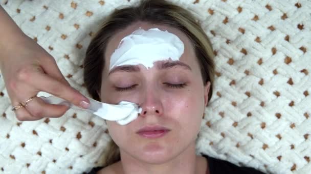 Μια λευκή αλγινική μάσκα εφαρμόζεται σε μια γυναίκα για να αναζωογονήσει το δέρμα της. — Αρχείο Βίντεο