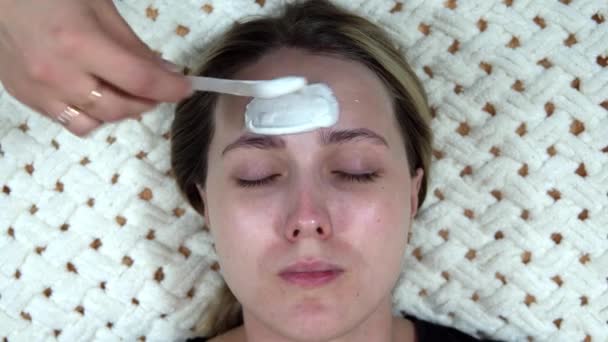 Uma máscara de alginato branco é aplicada a uma mulher para rejuvenescer sua pele. — Vídeo de Stock