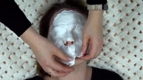 A white alginate face mask is removed for a woman to rejuvenate her skin. — Stock Video