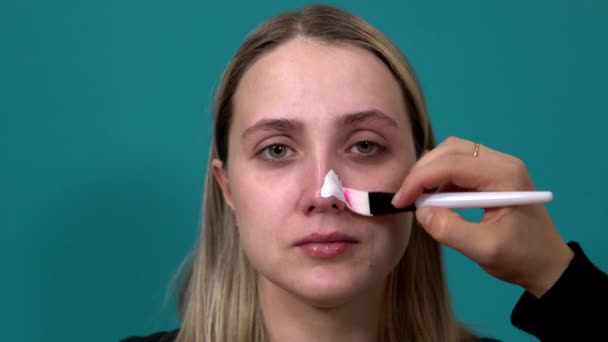 Mujer aplica una máscara blanca en la nariz contra las espinillas en la piel — Vídeo de stock