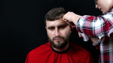 Zaman aşımı atışı. Bir kadın evinde, kuaförde, hızlı çekimde bir erkeğin saçını kesiyor.