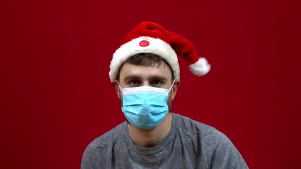 Un uomo con una maschera medica canta e balla con un cappello di Natale vivo danzante sulla testa — Video Stock