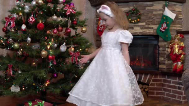 Uma menina de vestido está girando em torno da árvore de Natal. Atmosfera festiva antes do Natal e Ano Novo — Vídeo de Stock