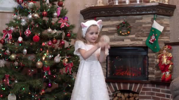 La jeune fille tient un souvenir sous la forme d'une boule de verre avec de la neige dans la main et la secoue. Ambiance festive avant Noël et le Nouvel An — Video