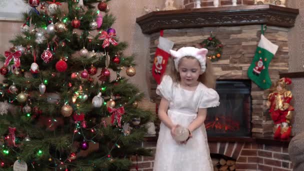 A menina segura uma lembrança na forma de uma bola de vidro com neve na mão e a balança. Atmosfera festiva antes do Natal e Ano Novo — Vídeo de Stock