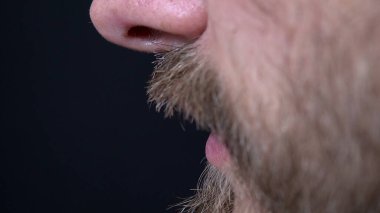 Siyah arka plan 4k 'de sakalını budamış bir adamın yakın çekimi.