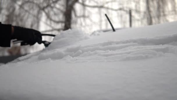 Un homme balaie la neige d'une voiture. En hiver en Russie, la voiture était couverte de neige — Video