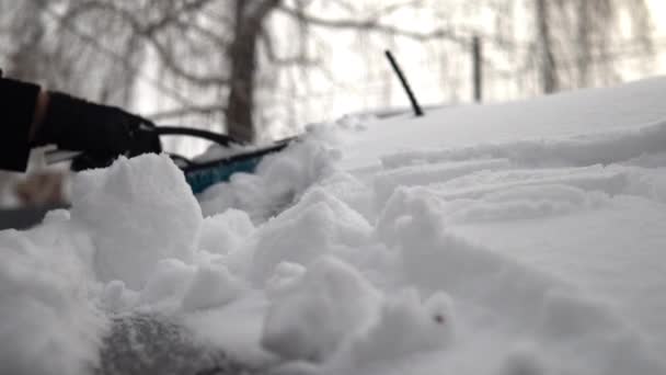 Un homme balaie la neige d'une voiture. En hiver en Russie, la voiture était couverte de neige — Video