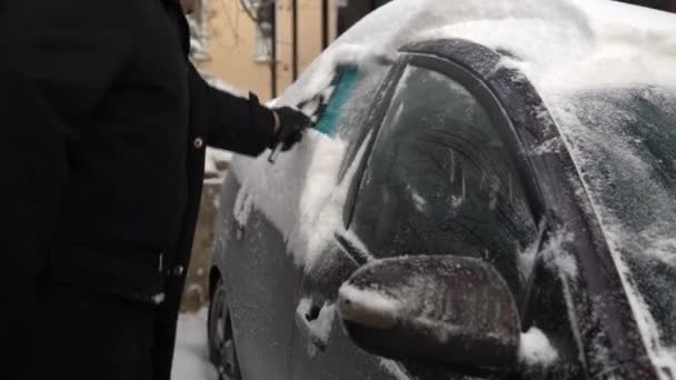 Reinigen einer Autoscheibe vom Schnee mit einer Bürste. Winter in Russland, das Auto war mit Schnee bedeckt — Stockvideo