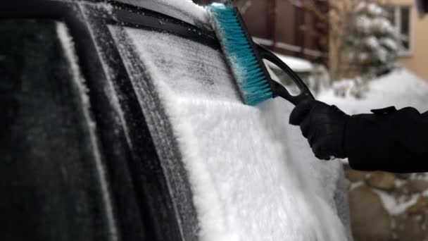 Rengör ett bilfönster från snö med en pensel. Vintern i Ryssland, bilen var täckt med snö — Stockvideo