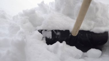 Küreğin yakın planında, bir adam bahçesinde kürekle kar temizliyor. Rusya 'da kış, avluyu karla kapladı.