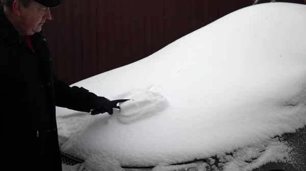 男は車のフードから雪を磨く ロシアの冬 車は雪に覆われていました4K — ストック写真