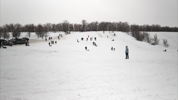 A crowd of people ride on snow slides. Children list themselves on the ice slide on inflatable rings. sledges, plastic skating rinks. Shooting time-lapse video — Stock Video