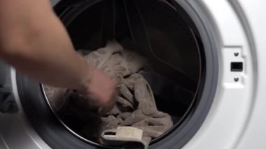 Kız kirli çamaşırları çamaşır makinesine yüklüyor.