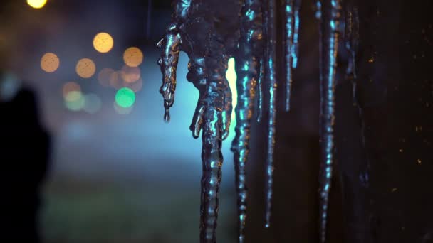 Rus kış akşamı. Buz saçakları sıcak havadan erir, arka planda neon ışığı. — Stok video