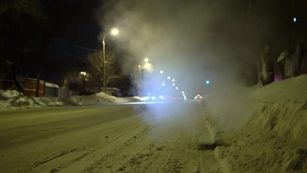 俄罗斯冬季道路在晚上。水蒸气从路上的下水道炉栅里冒了出来 — 图库视频影像