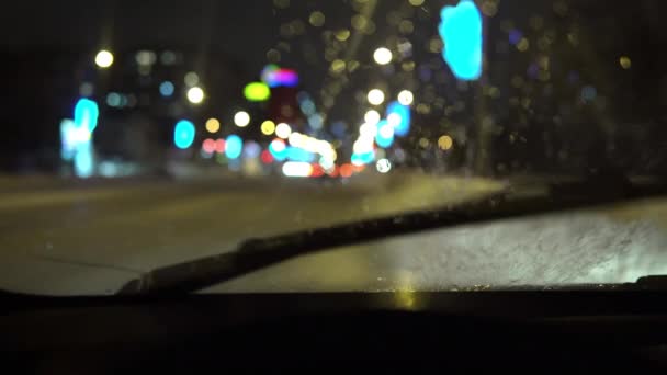 Närbild från bakom ratten på en bil, vattenstänk på vindrutan och borstar arbete — Stockvideo