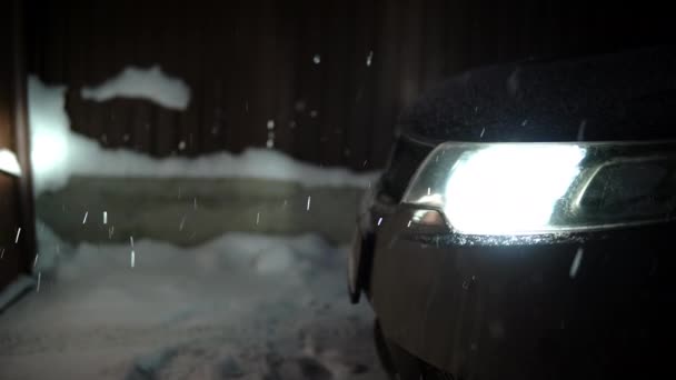 Autoscheinwerfer beleuchten fallenden Schnee am Abend — Stockvideo