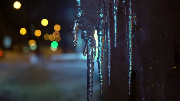 Winter Russian evening. Icicles melt from warm air, neon light in the background — Stock Photo, Image