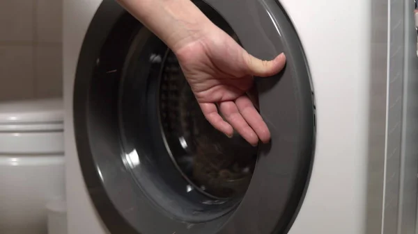 Meisje laadt vuile dingen in de wasmachine close-up — Stockfoto