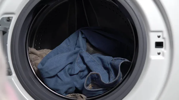 Meisje laadt vuile dingen in de wasmachine close-up — Stockfoto