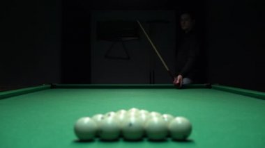 Beyaz bilardo topu piramidini kırmak üzere olan bir adam. Bilardo oyununun başlangıcı.