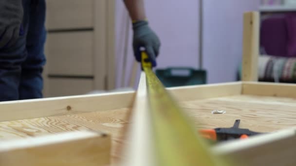 Muž měří kus dřeva pomocí pásky. Muž dělá domácí opravy.. — Stock video