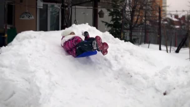 Ένα κορίτσι ιππεύει σε μια χιονοστιβάδα στη ρωσική αυλή. Πυροβολισμός σε αργή κίνηση — Αρχείο Βίντεο