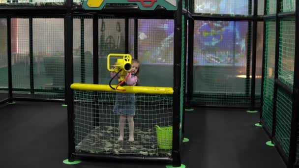 Çocuk parkında bir kız ağır çekimde sarı bir hava topuyla toplara ateş ediyor. — Stok video