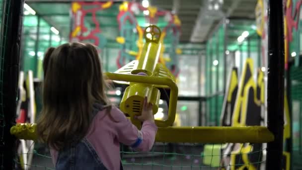 Dziewczyna na placu zabaw strzela kulkami z żółtego działa powietrza — Wideo stockowe