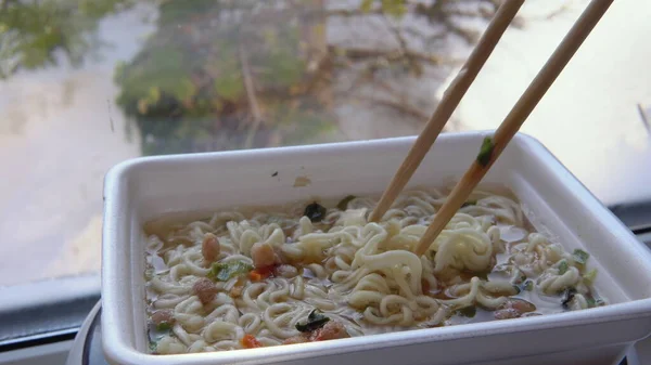 Stir the noodles with Chinese chopsticks into the top ramen. Brewing instant noodles Royalty Free Stock Images