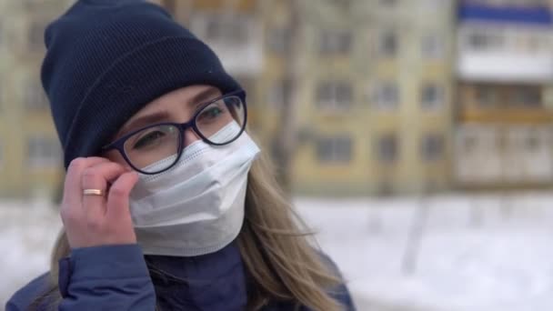一个戴眼镜的女孩站在街上，摘下外科口罩，松了口气 — 图库视频影像