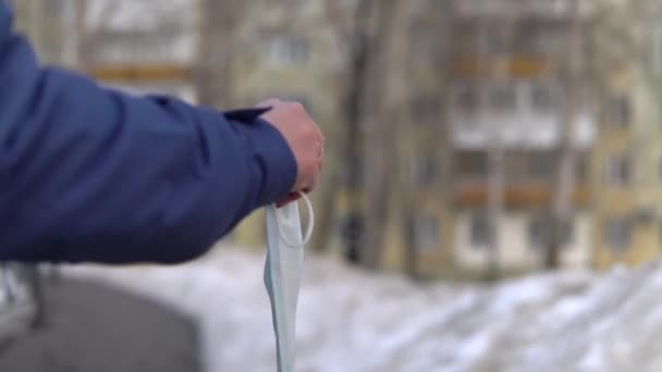 Крупный план, где взрослая человеческая рука бросает хирургическую маску в мусорный бак — стоковое видео