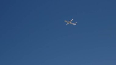 Mavi gökyüzünde, bir uçak kalkış yükseklik kazanıyor.