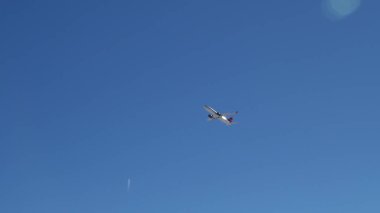 Mavi gökyüzünde, bir uçak kalkış yükseklik kazanıyor.