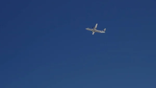 Na modrém jasném nebi vzlétá letadlo a nabírá výšku. — Stock fotografie