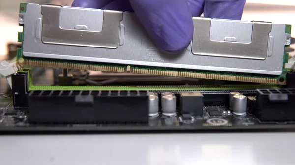 El técnico de reparación inserta una memoria RAM en el zócalo de la placa base. Mantenimiento y modernización de un ordenador personal — Foto de Stock