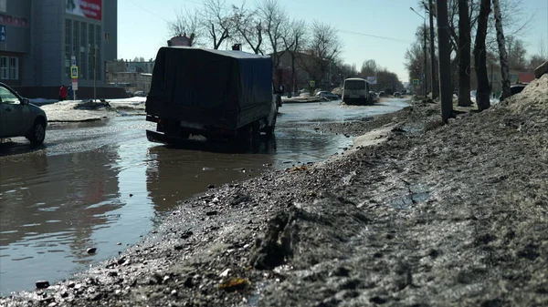 時間の経過写真、車はロシアの浸水した道路に沿って運転している。トラックは大きな水たまりの中で止まった ロイヤリティフリーのストック写真