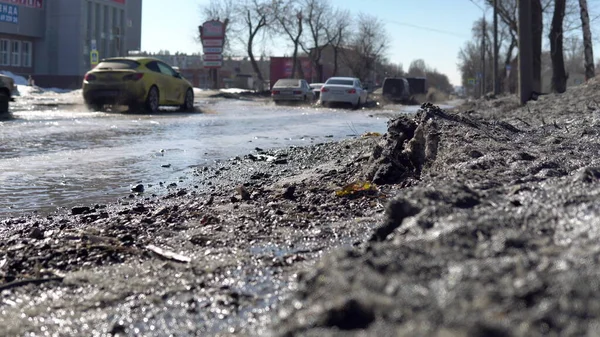 在俄罗斯，汽车正沿着一条被洪水淹没的道路行驶。融化的雪淹没了道路 图库照片